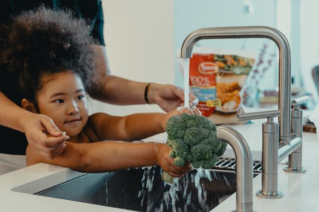 parent-helps-child-wash-broccoli