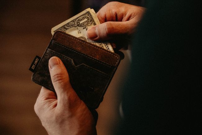 person pulls one dollar bill out of wallet