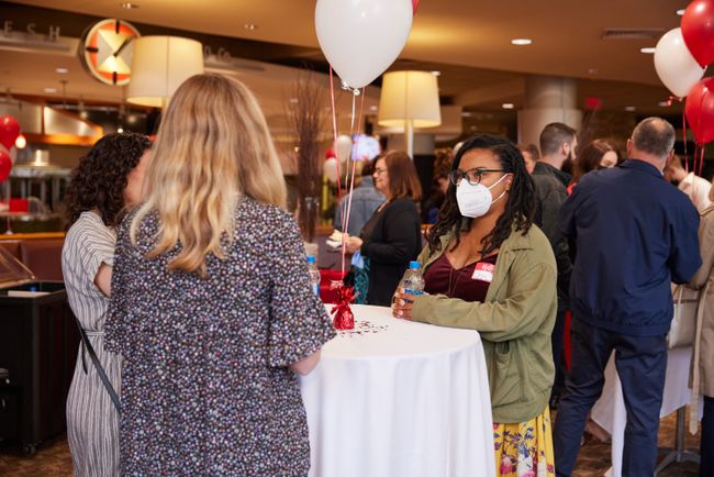 Photo of guests at high-tops with red and white balloons at the pre-commencement reception
