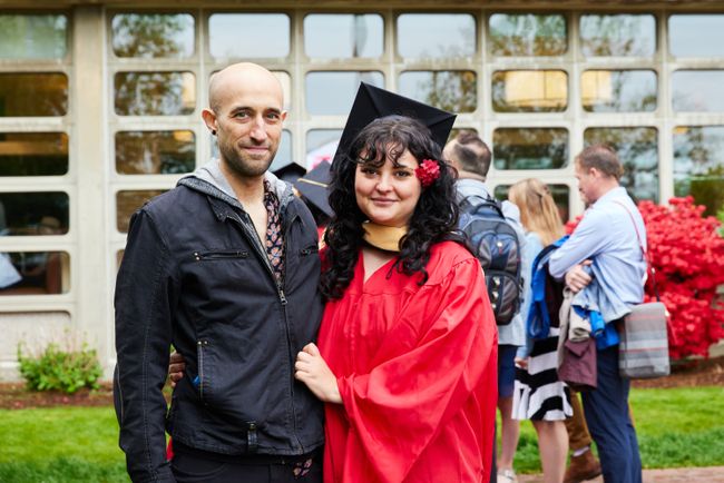 A graduate and their guest pose for a photo outside