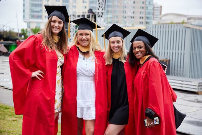 Four grads pose for a picture in front of Nickerson Field