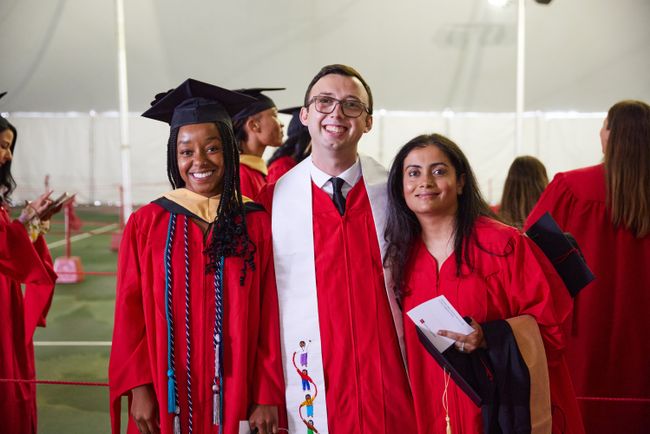 Three graduate pose for a picture in the line-up tent