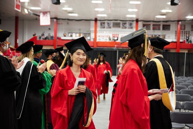 A grad smiles for a photo as they walk through the procession