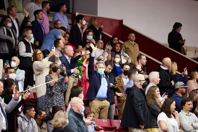Guests in the stands take pictures and wave to grads