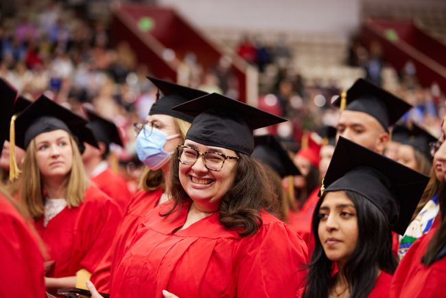 A grad smiles from the arena floor
