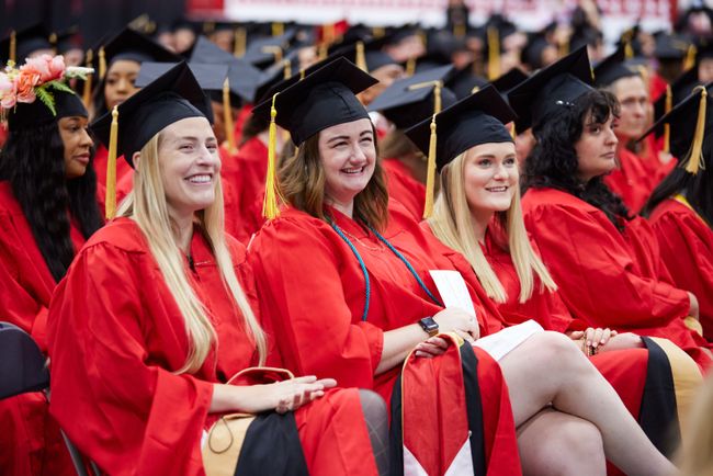 Grads smile up at their fellow graduates from their seats