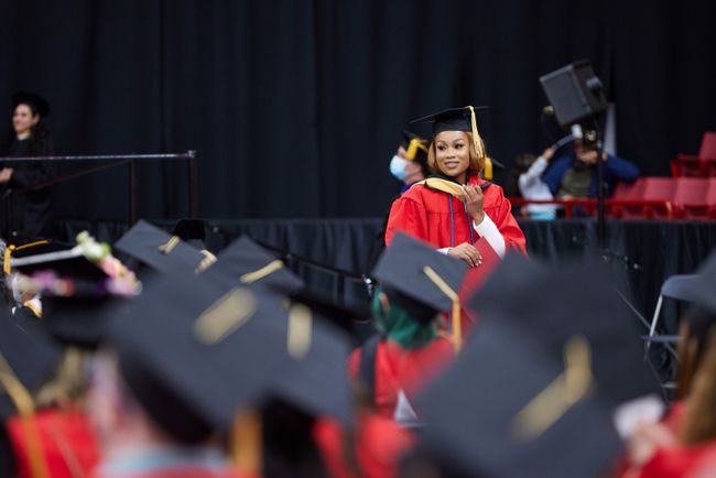 A graduate walks back to her seat touching her hood