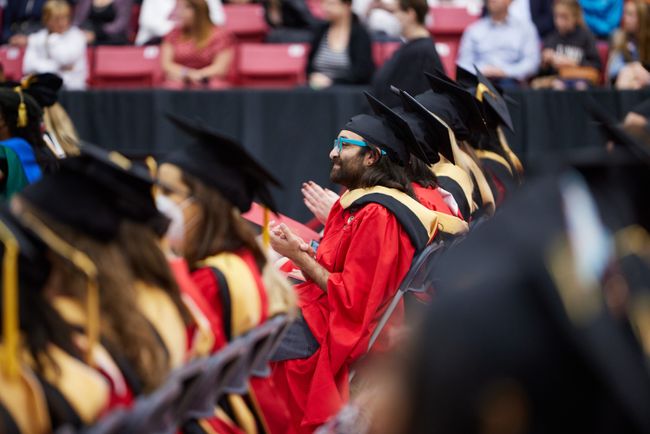 Graduates clap from their seats