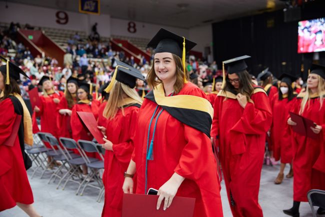 A grad smiles at the camera as they walk to the reception