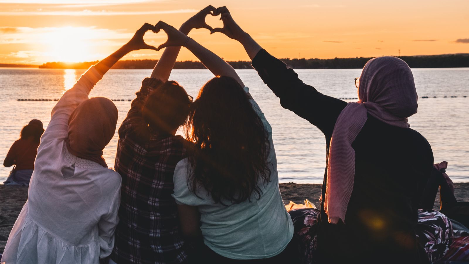 friends sit together on a beach