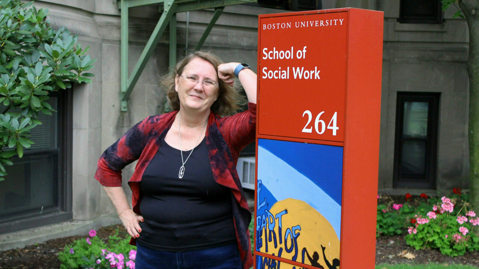 Lecturer Michelle Walsh poses in front of BUSSW next to School of Social Work sign