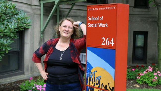 Lecturer Michelle Walsh poses in front of BUSSW next to School of Social Work sign