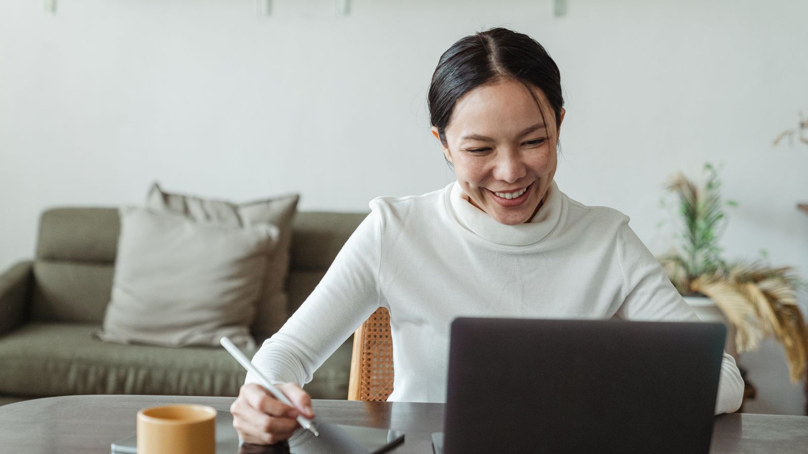 Woman sitting in home office smiles at laptop