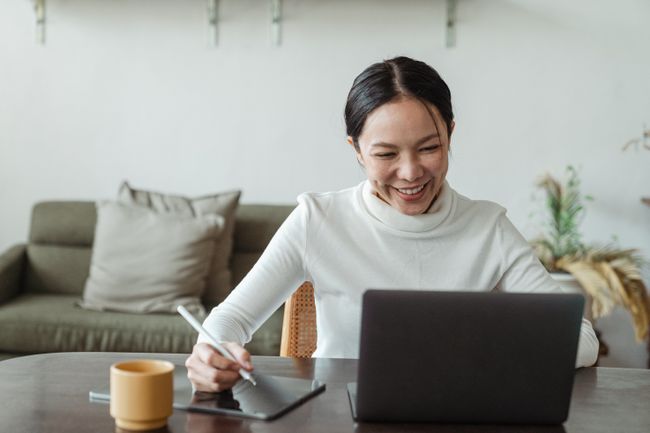 Woman sitting in home office smiles at laptop