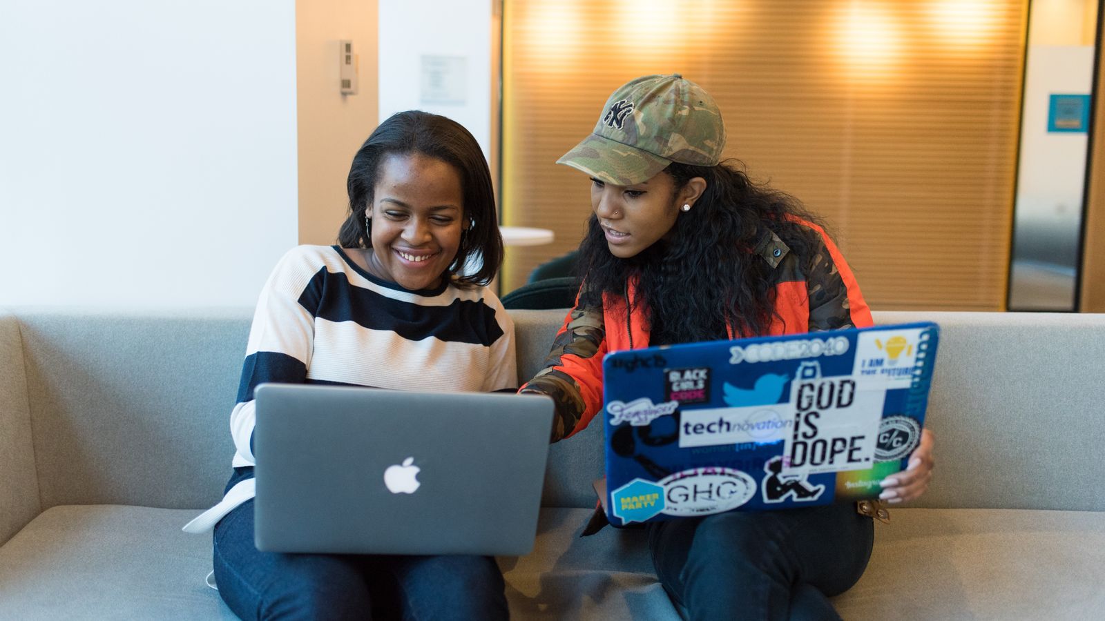 two girls look at a computer together