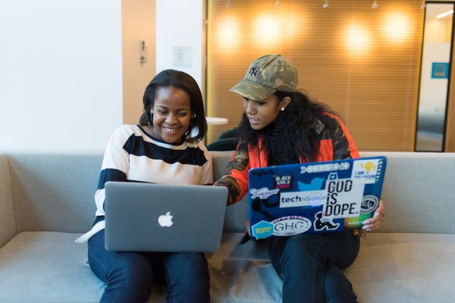 two girls look at a computer together