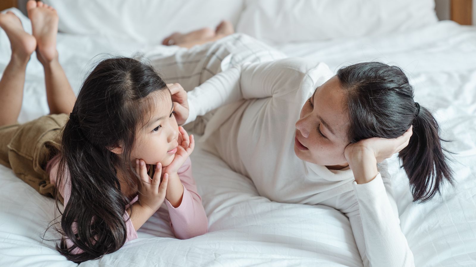 Photo of Woman and Girl Talking While Lying on Bed