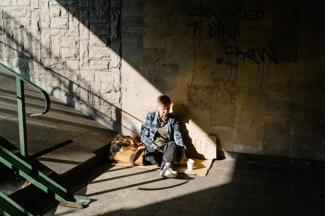 older woman sitting on ground with belongings