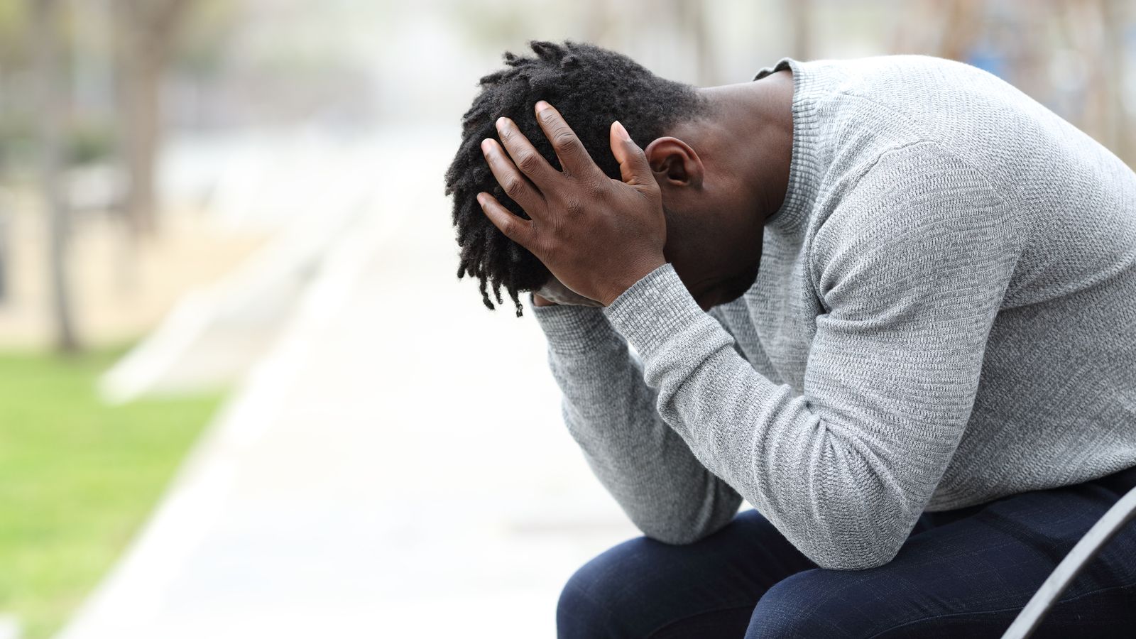 a black man holds his head in his hands