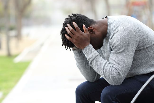 a black man holds his head in his hands
