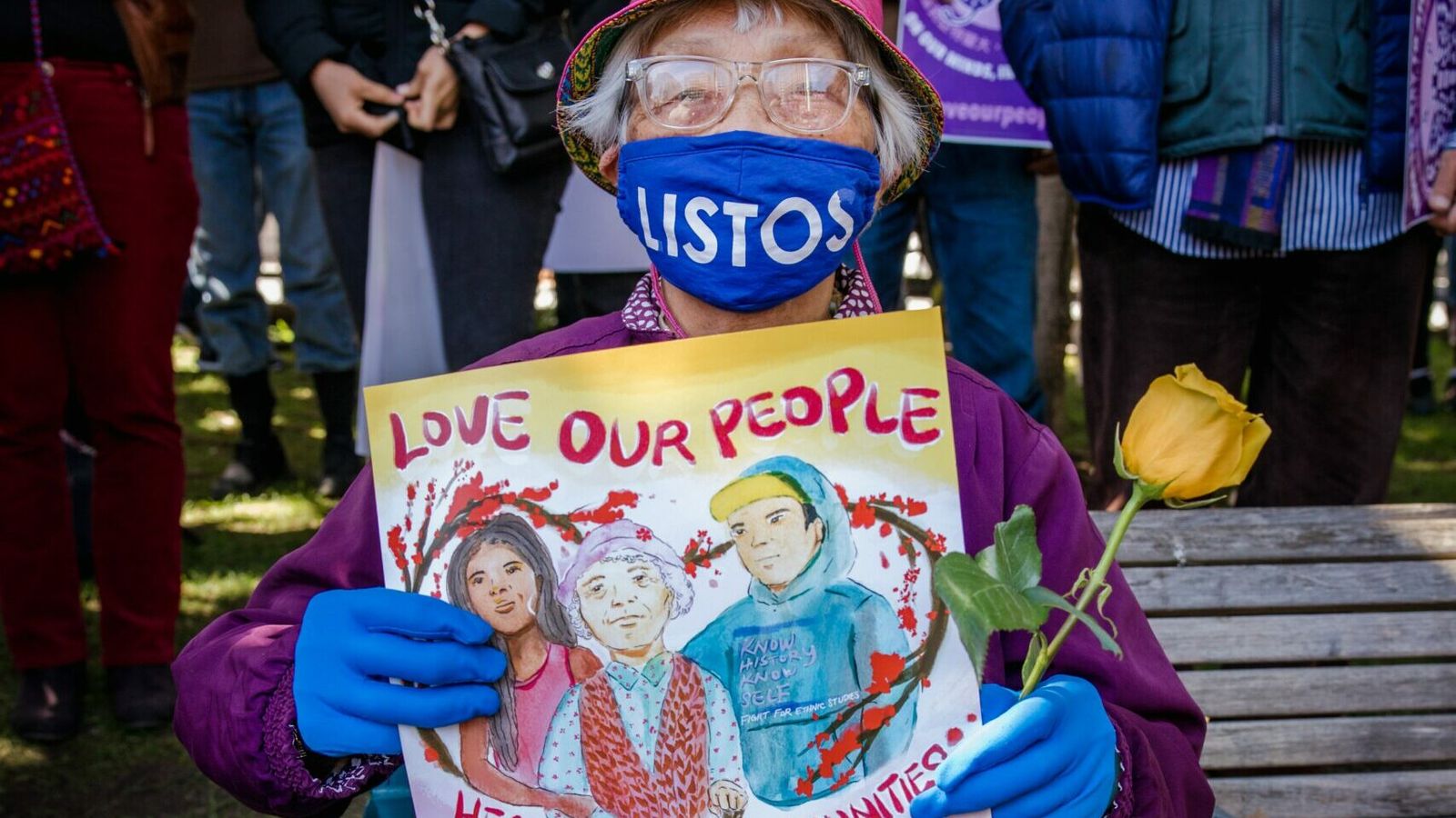 a woman holding a sign that says "love our people, heal our communities"