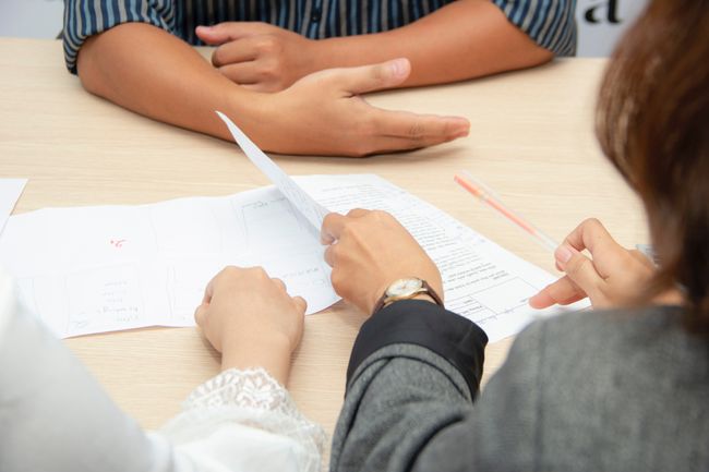 three people looking over papers together at a table