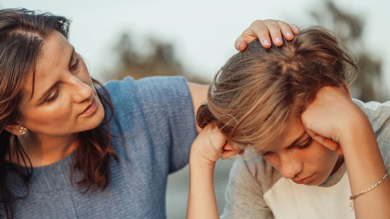 woman in blue shirt talking to boy in white shirt