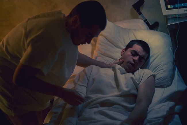 Man in hospital bed being examined by medical practioner