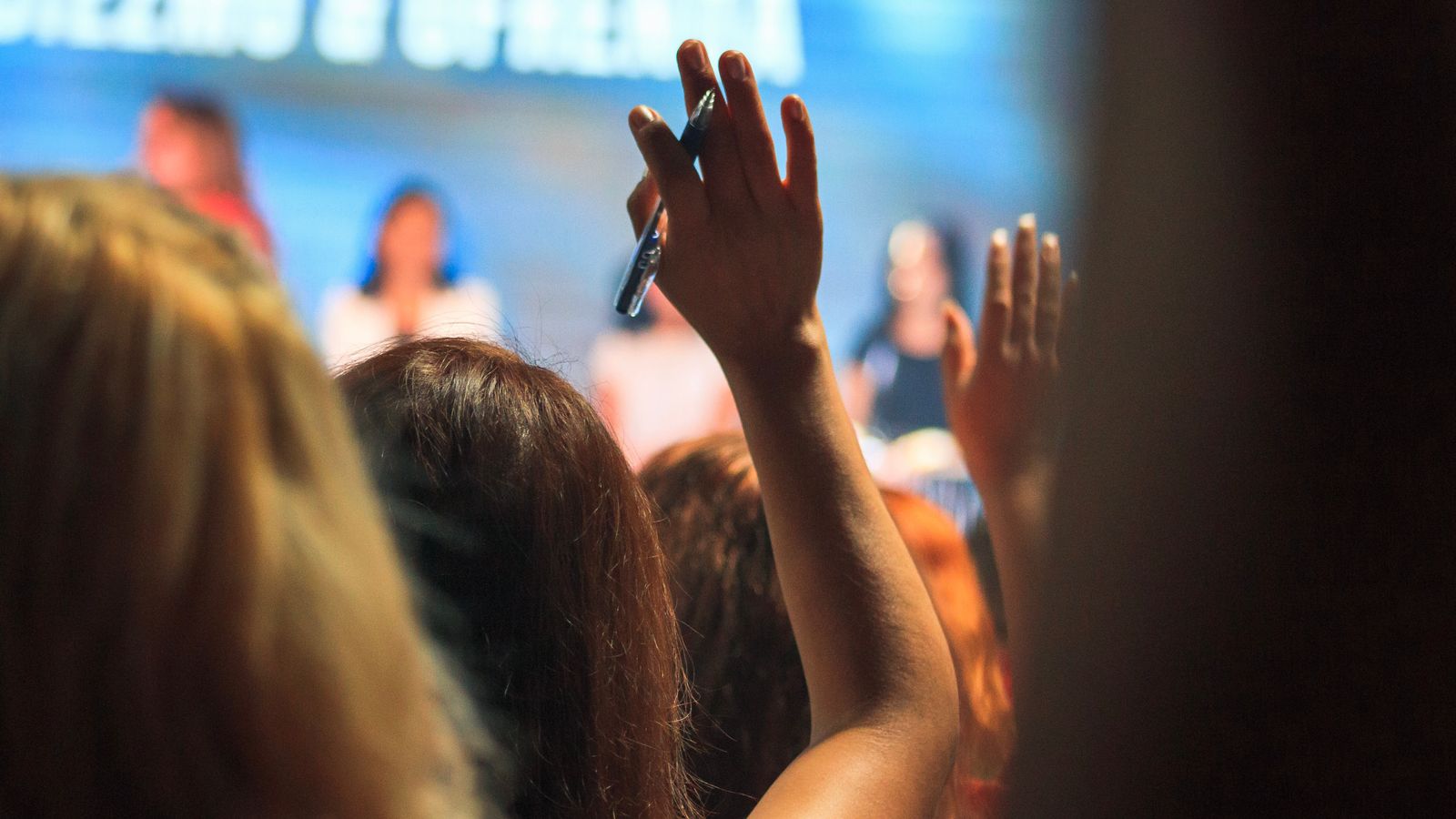 Audience members raising their hands at event