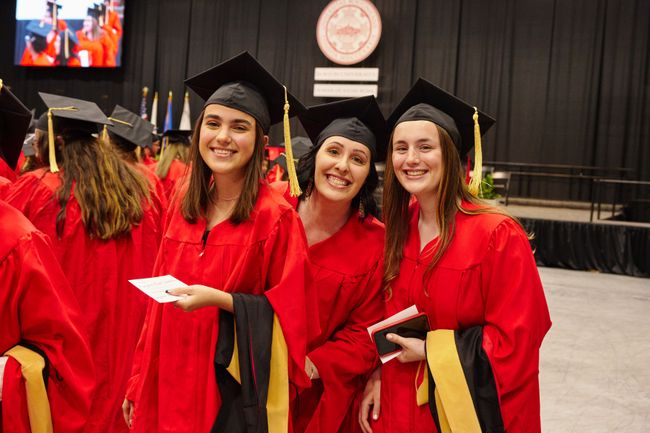 Graduates smile for photo in Walter Brown Arena