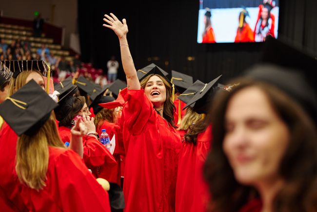 Graduating student turns to wave at someone behind them