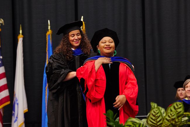PhD graduate is hooded on stage