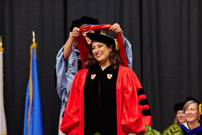 PhD graduate is hooded on stage