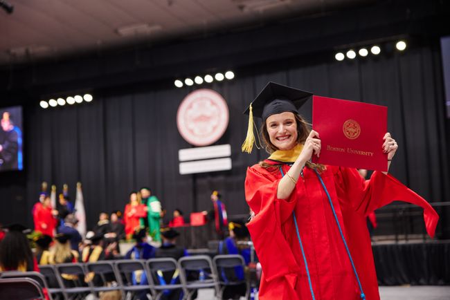 Smiling graduate walks back to seat with diploma