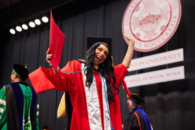 Smiling graduate walks back to seat with diploma