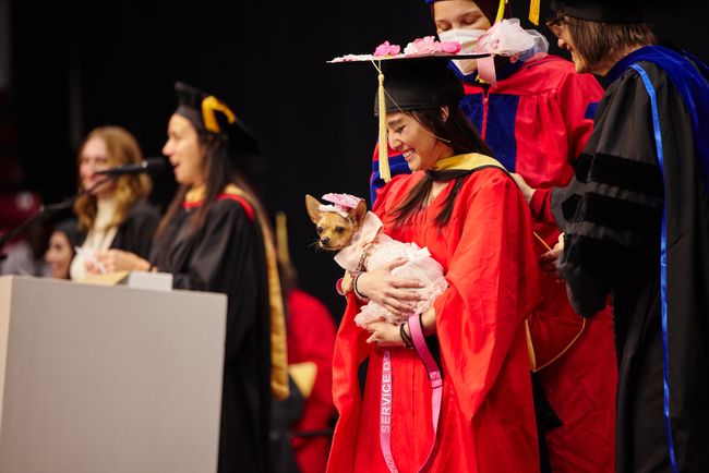 Graduate holds service dog in matching outfit