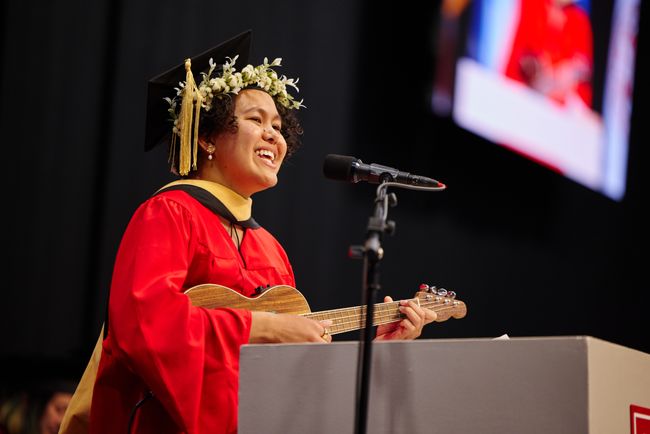 Graduate performs original song on stage with ukelele