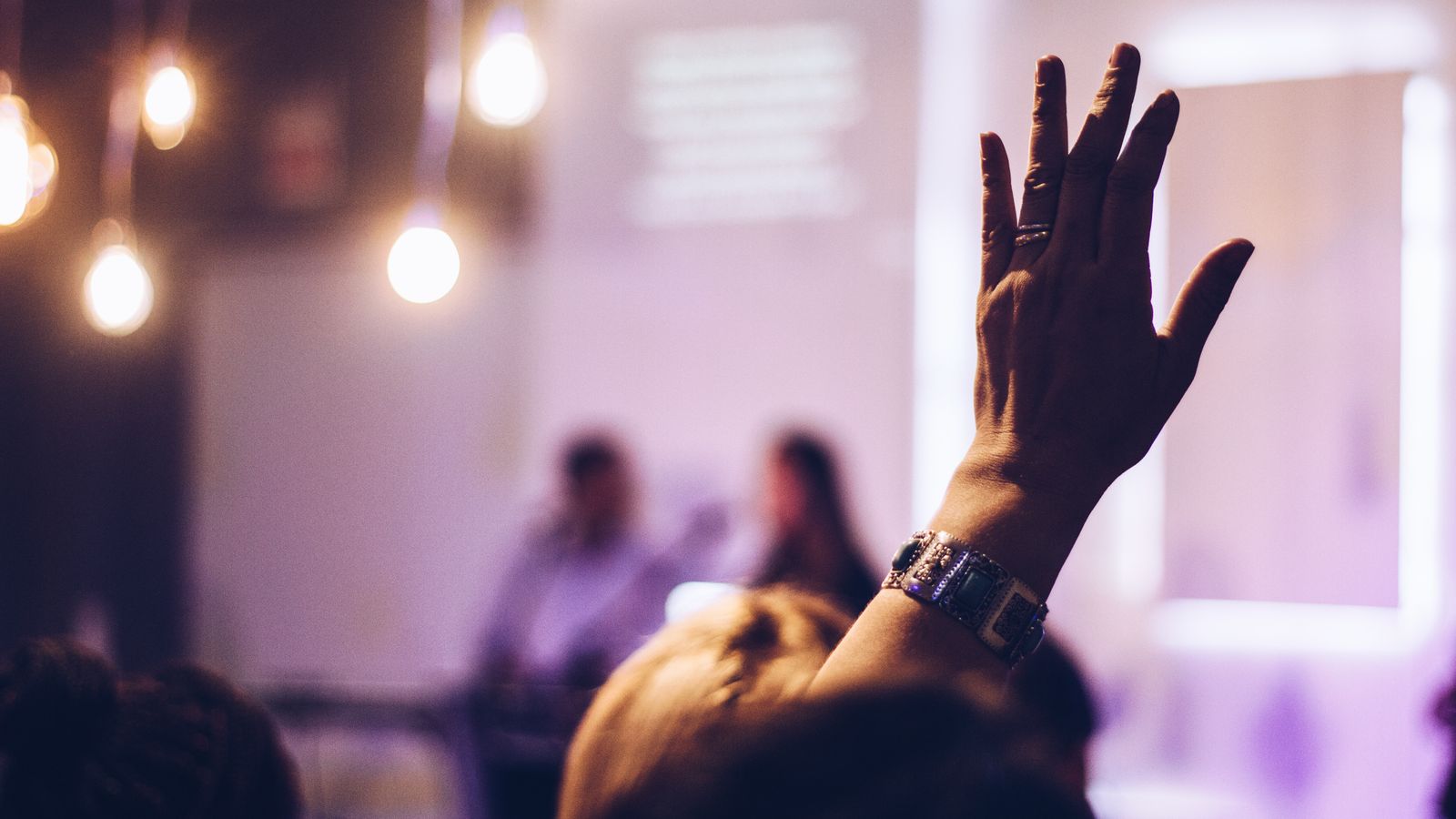 Audience member raises hand at indoor event