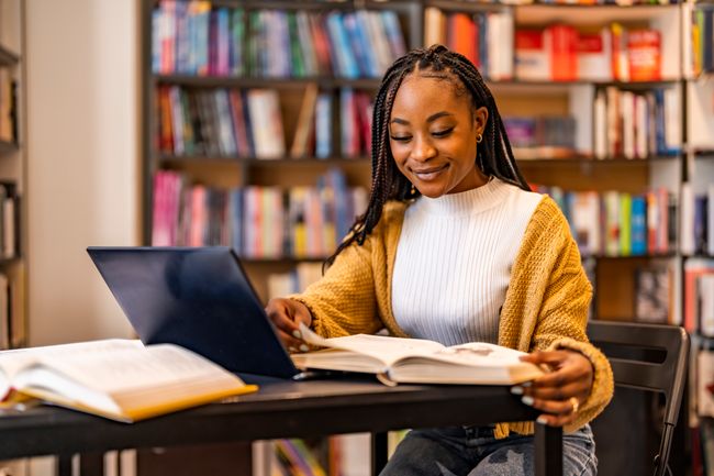 a student writing a research paper in a library