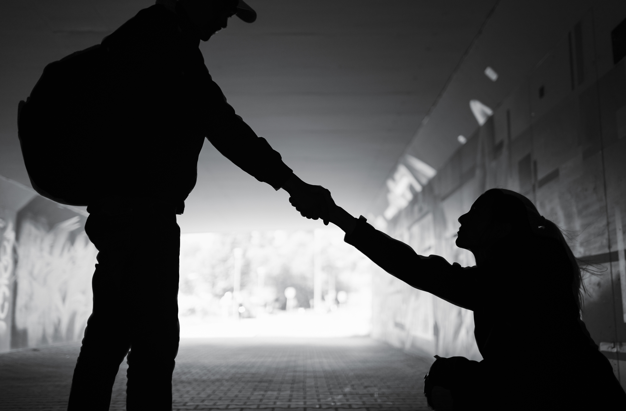 a photo of two people in a tunnel. one person is helping another person up.