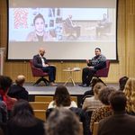 Photo of the event moderator and author on stage in front of audience