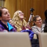 Photo of audience members looking towards stage and smiling