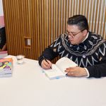 Photo of BUSSW Prof. Luis Alvarez-Hernandez signing a copy of See Me! during the reception and book signing