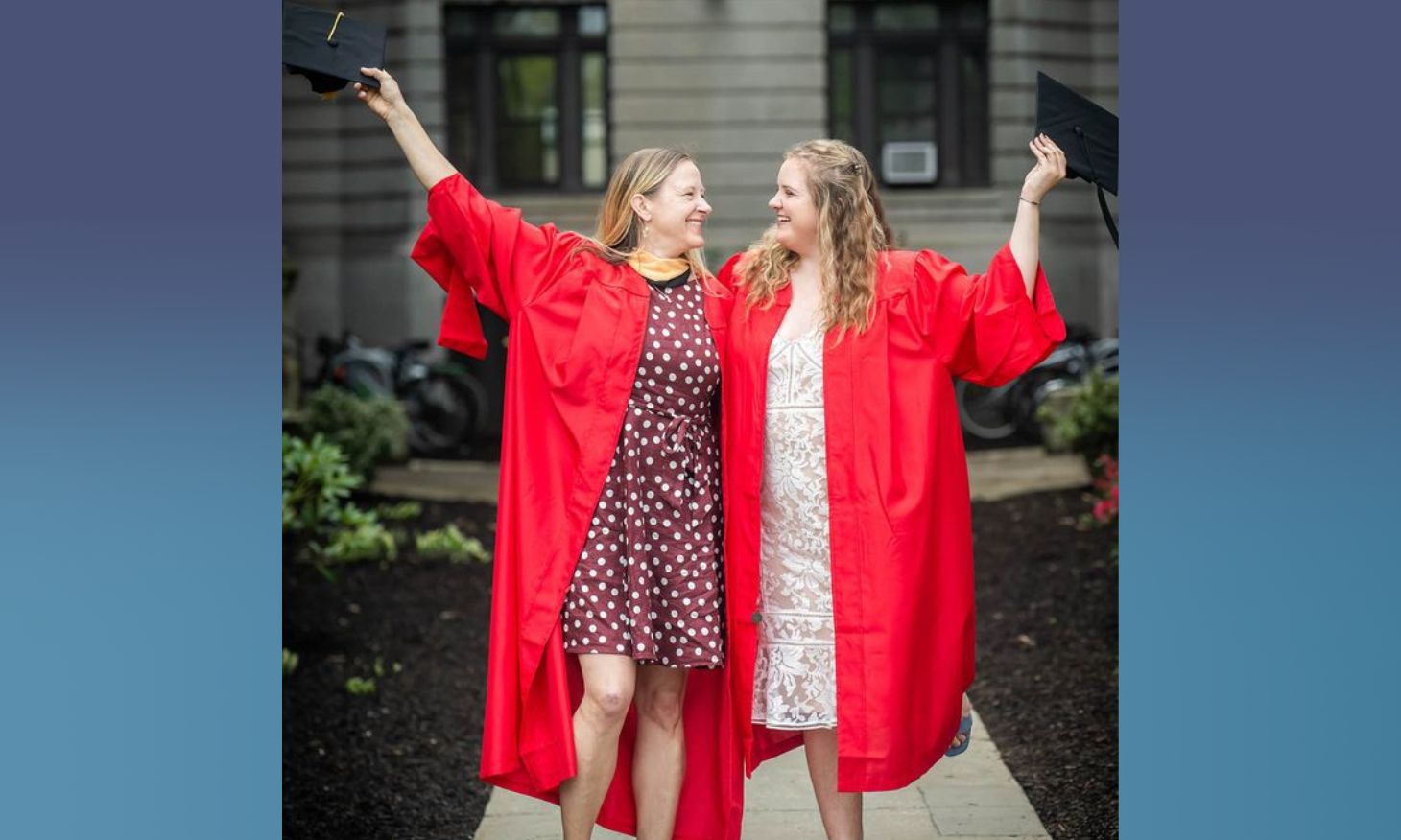 A photo of Caren and Annica Hunter celebrating in commencement robes outside of BU School of Social Work building