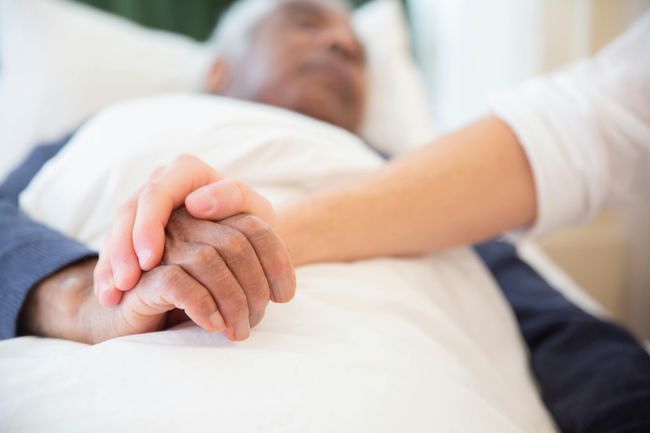 person holding hand of patient lying down