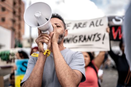 Mature man talking in a megaphone during a protest in the street