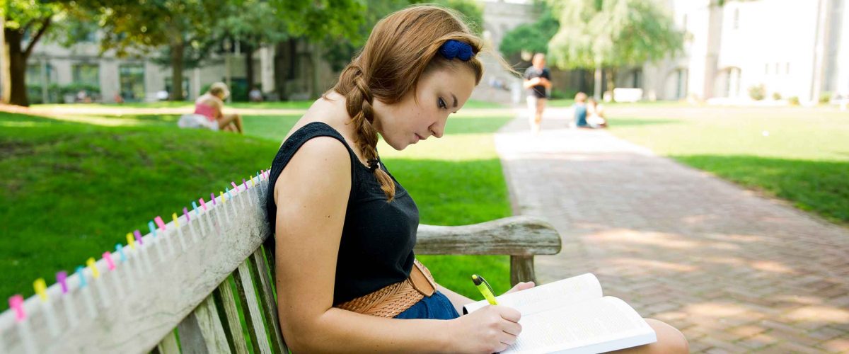 A Boston University student underlines passages in a book.