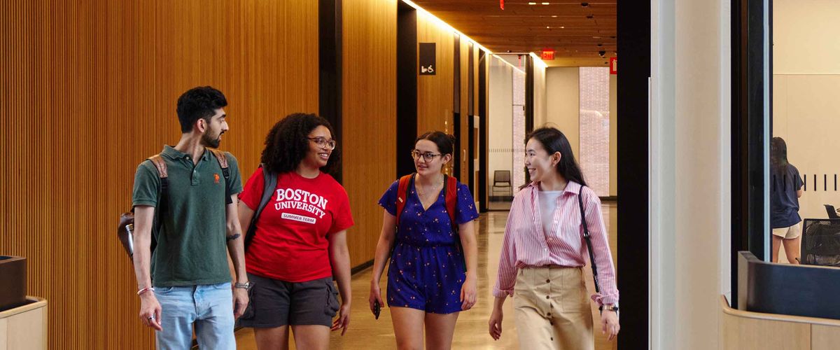Four Boston University students walk through the halls of a modern building
