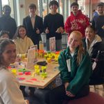 undergraduate students and their instructor sit around an activity table at an event