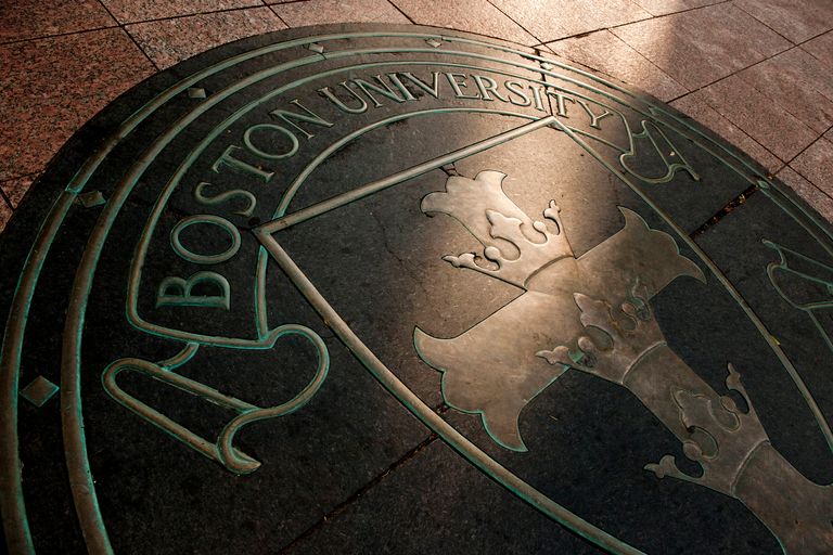 Close-up of Boston University seal embedded in a stone floor with ornate cross design.